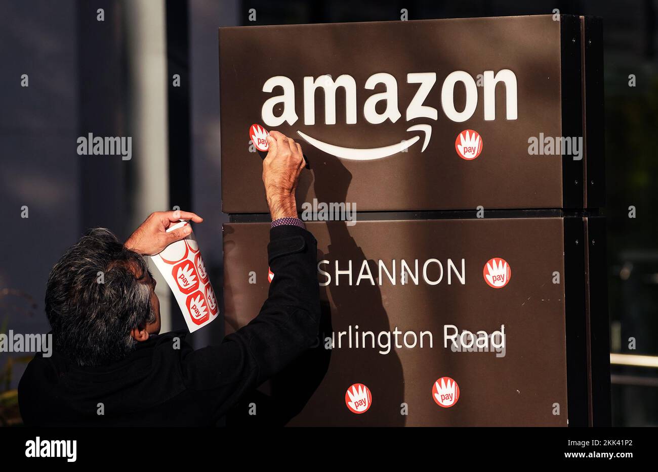 A man places stickers on the Amazon logo during a protest outside