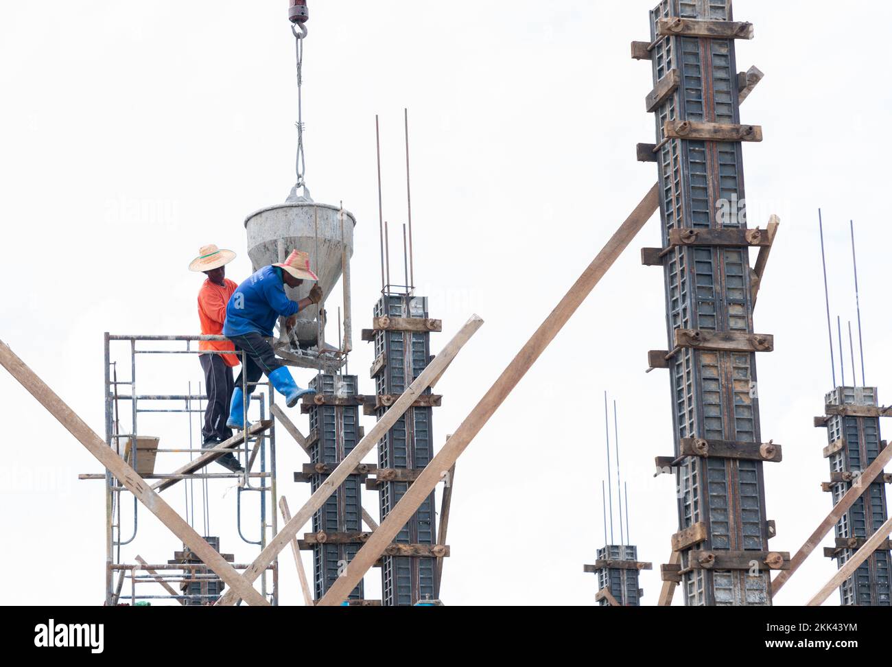 A worker is using a crane to lift the mortar to cast the structural