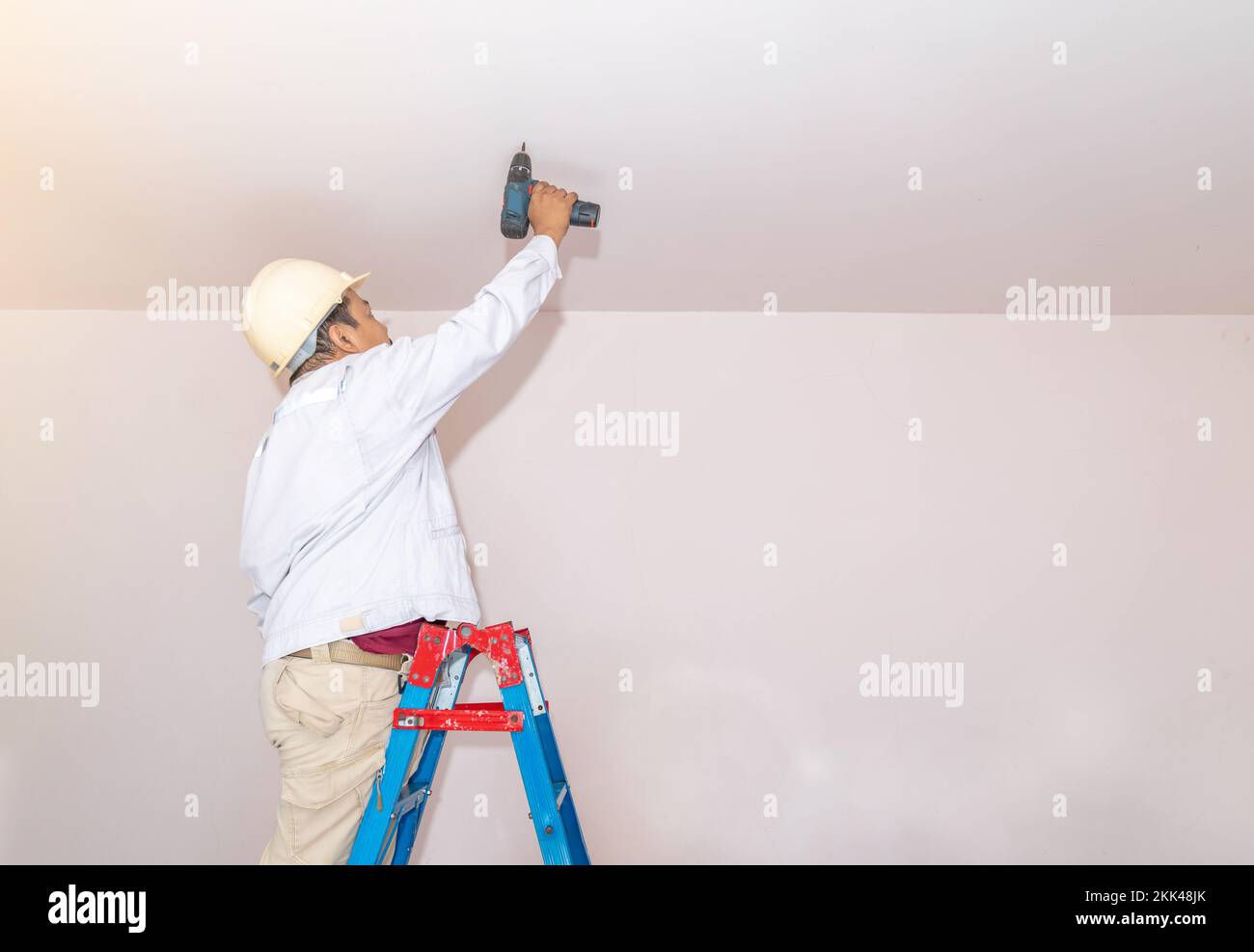Craftsman technician are repair drilling or fixing ceiling the wire socket with electrical drill or screwdriver. Stock Photo