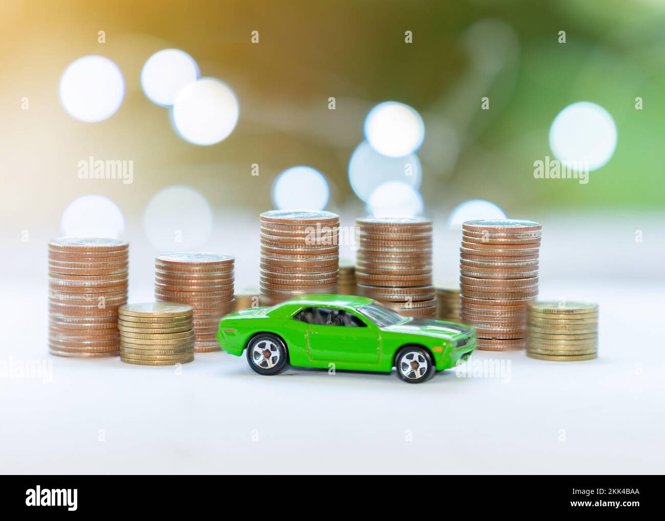 Coin stack and green car concept of saving money for a car on blur