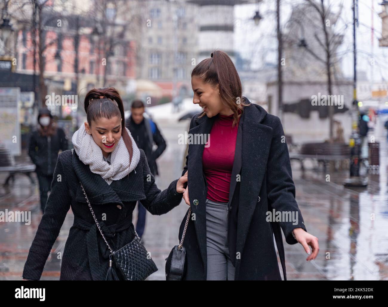 Two attractive and beautiful women are walking together on the rain ...