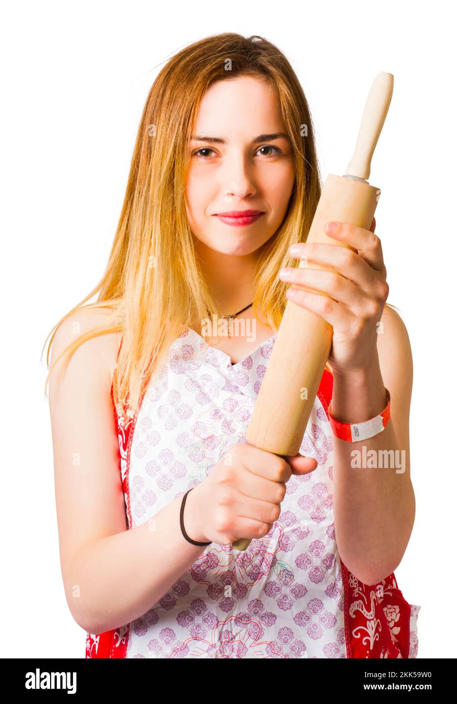 Young woman in apron holding wooden rolling-pin and looking at camera Stock Photo