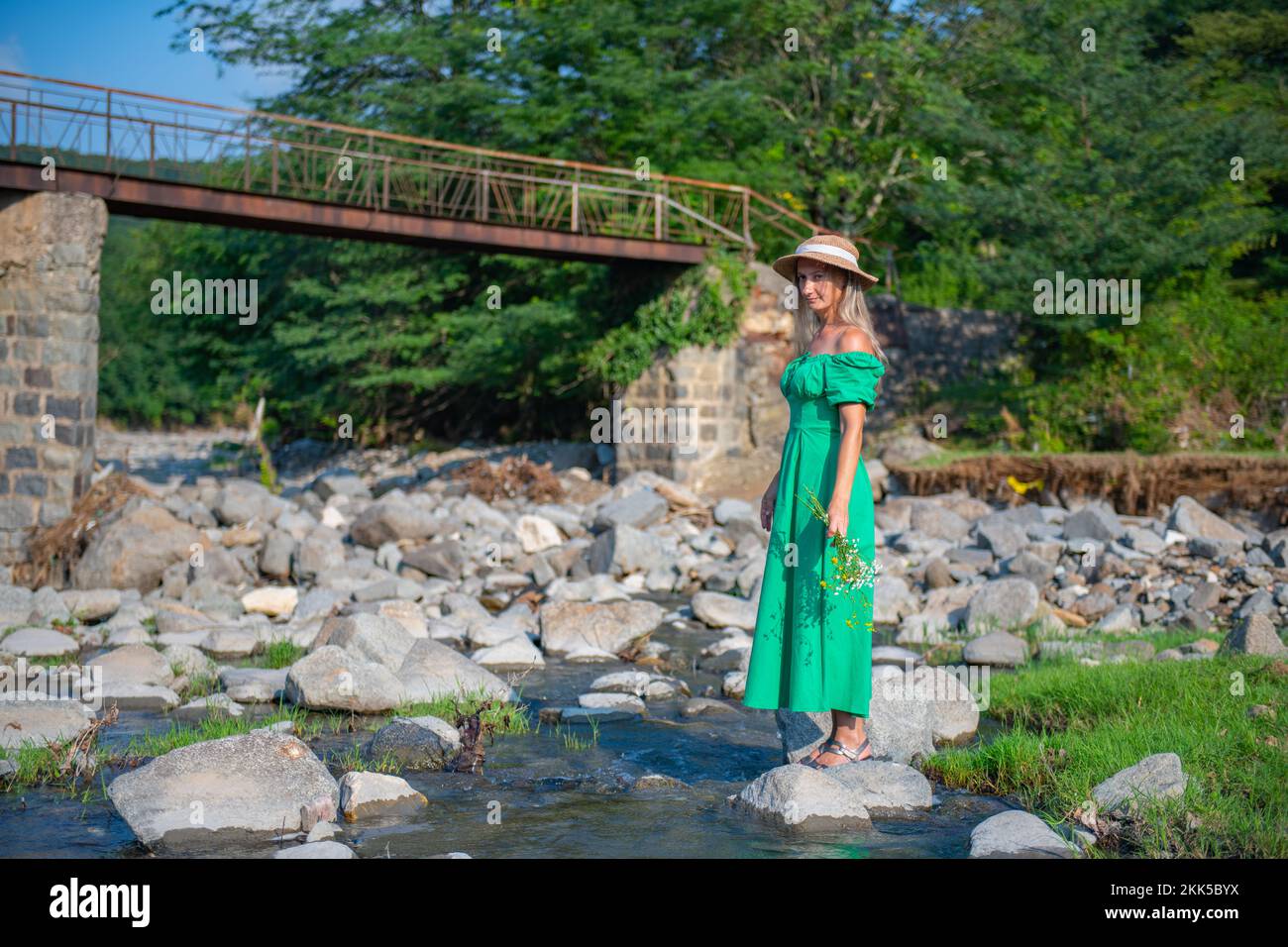 a woman in a green dress is standing by the river Stock Photo - Alamy