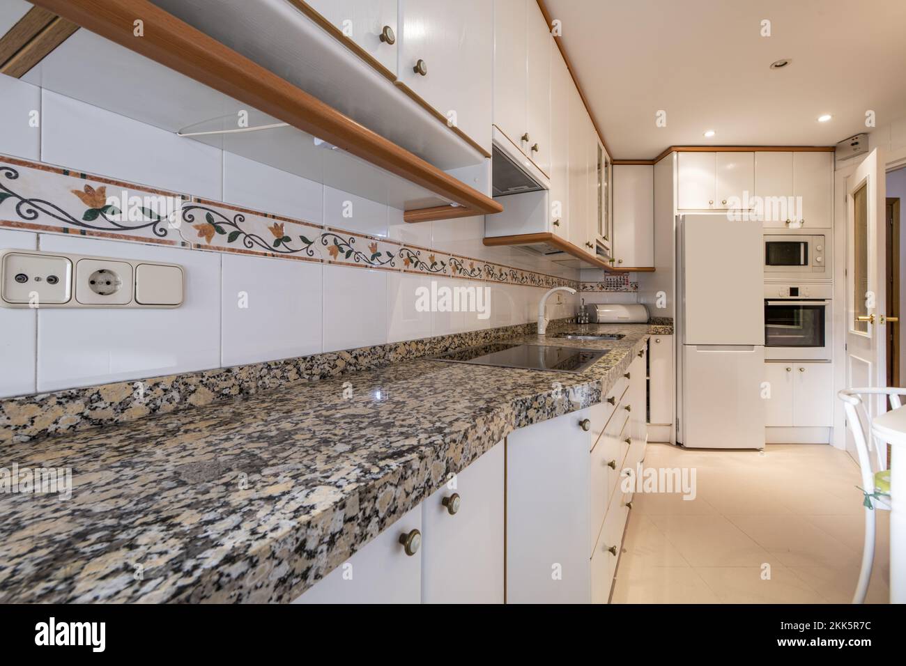 Kitchen of a house with a long wall covered in white with