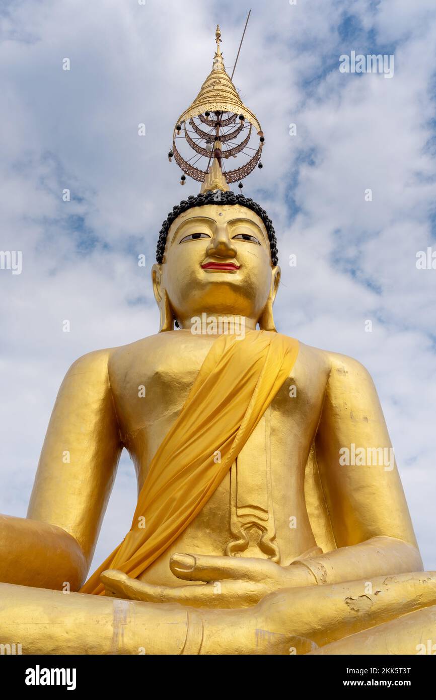 Low angle view of golden buddha statue on blue sky with clouds