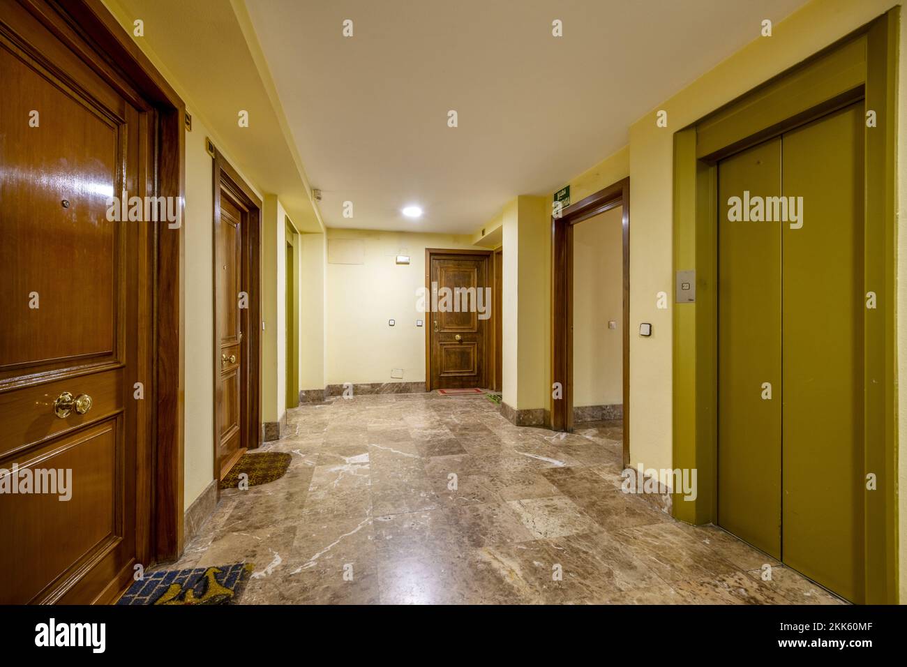 Landing of a residential apartment building with brown marble floors and ocher green metal elevator Stock Photo