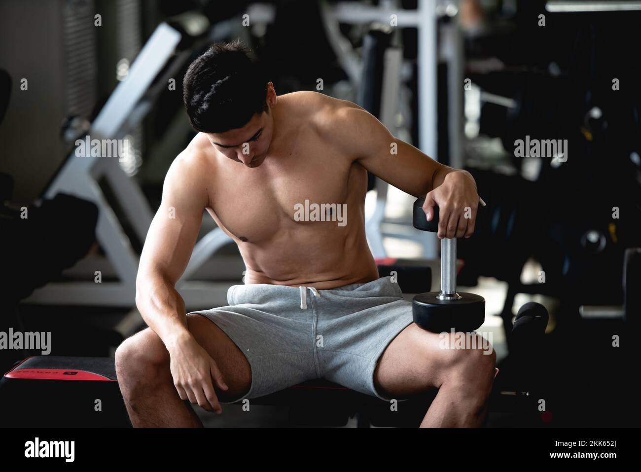 Asian young man workout, lifting with dumbbell to build muscle in