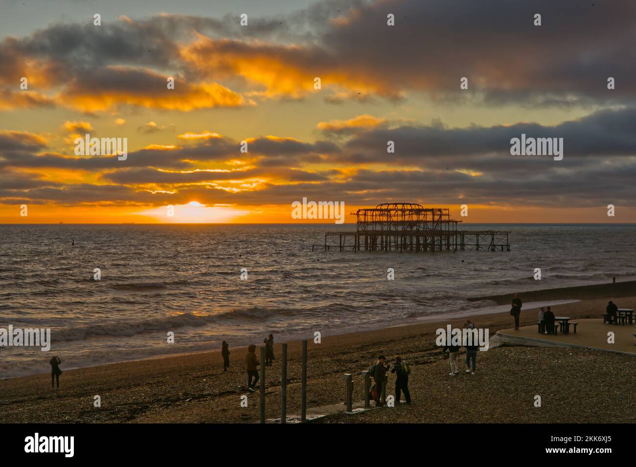 Ruined West Pier, seafront and beach in sunset with people. Brighton in East Sussex, England Stock Photo