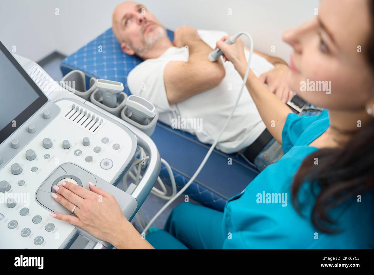 Woman performing ultrasound examination of elbow joint to a man Stock Photo