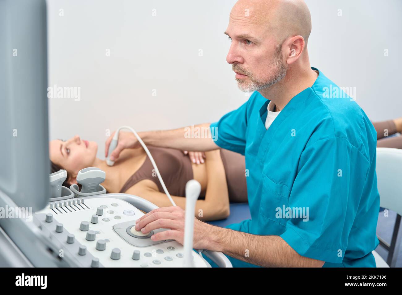 Doctor examines thyroid gland on monitor of the ultrasound machine Stock Photo