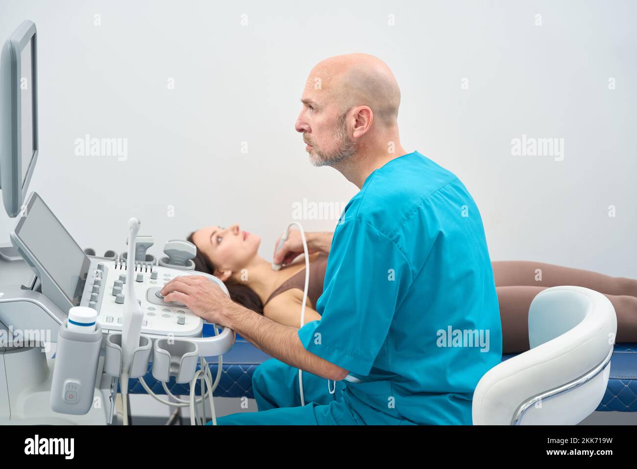 Bald doctor conducts a patient reception in ultrasound examination cabinet Stock Photo
