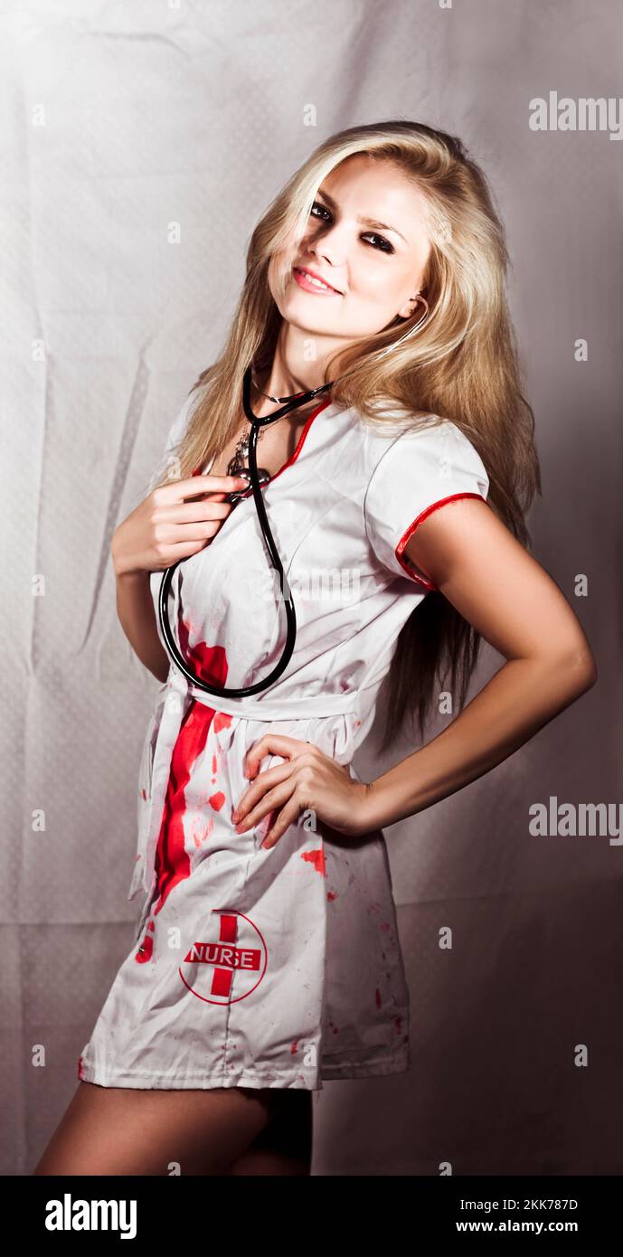 Evil Nurse Concept. Smiling pretty evil nurse wearing a stethoscope and