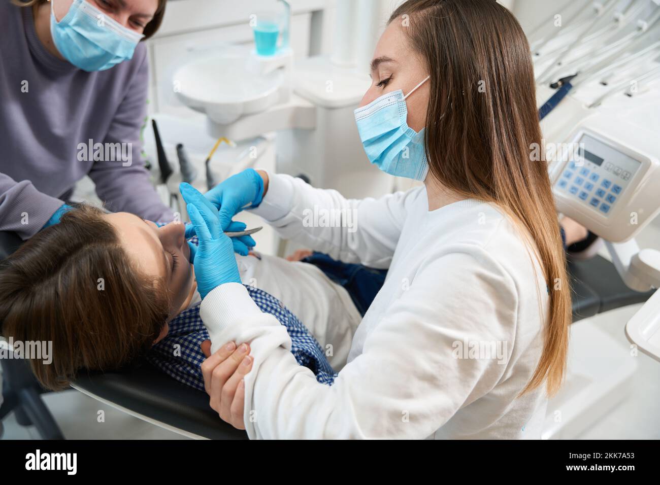 Woman dentist removes a tooth to a young patient Stock Photo Alamy