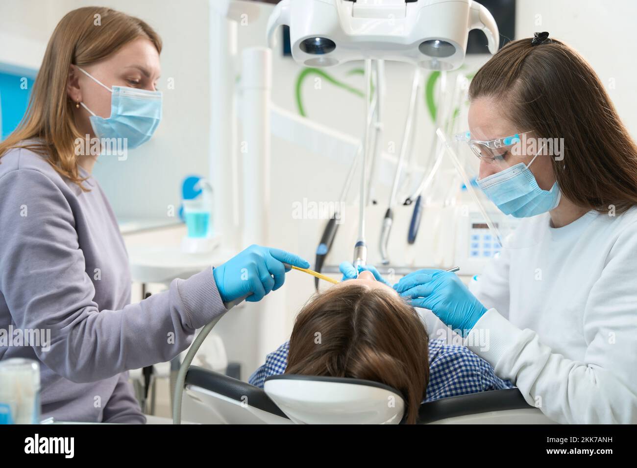 Woman doctor performs a dental procedure on a young patient Stock Photo