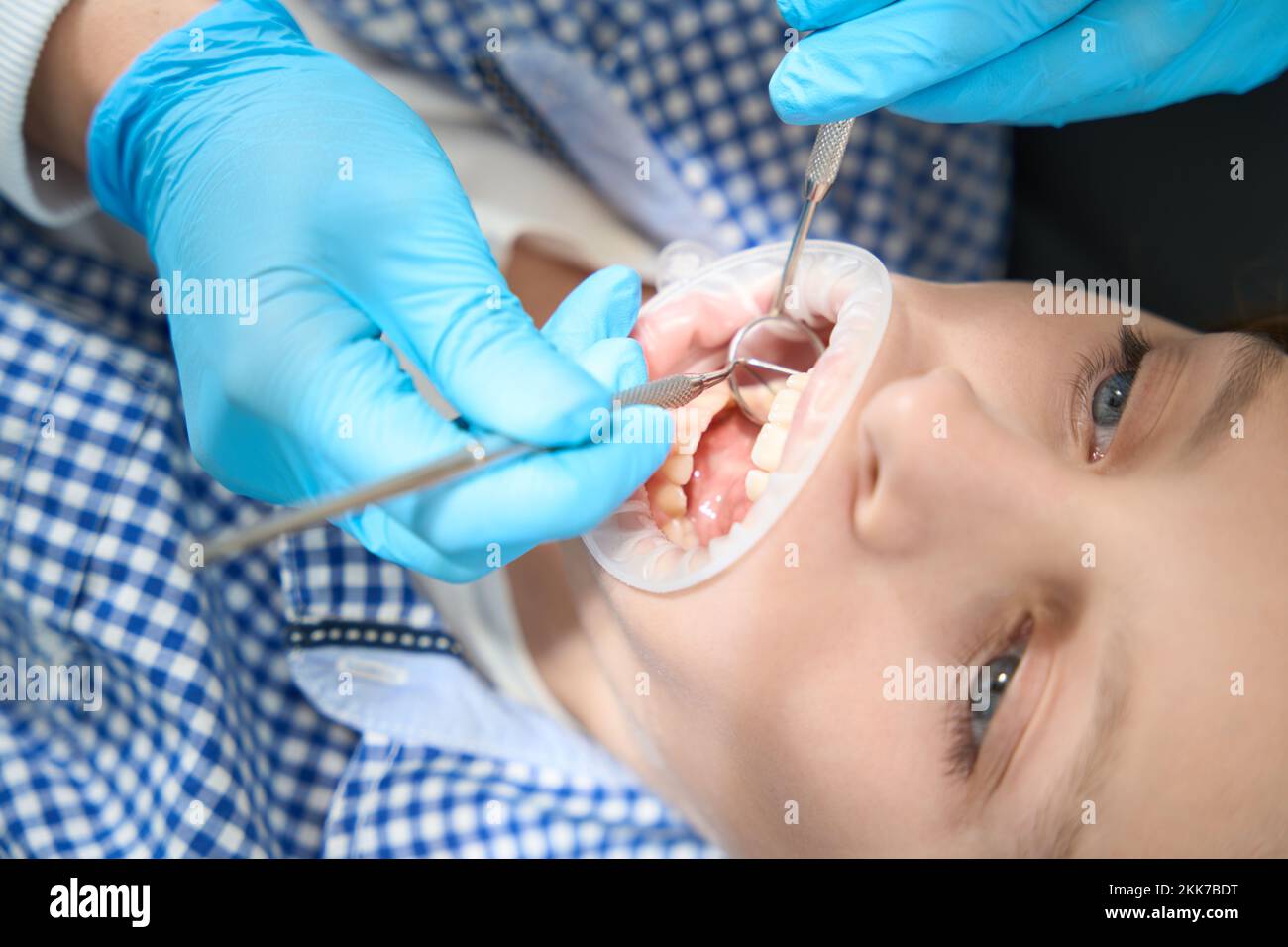Dentist performs a professional oral hygiene procedure to young patient Stock Photo