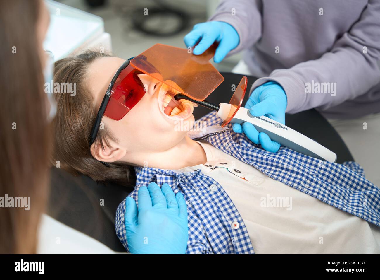 Young patient in protective glasses lies in a dental chair Stock Photo