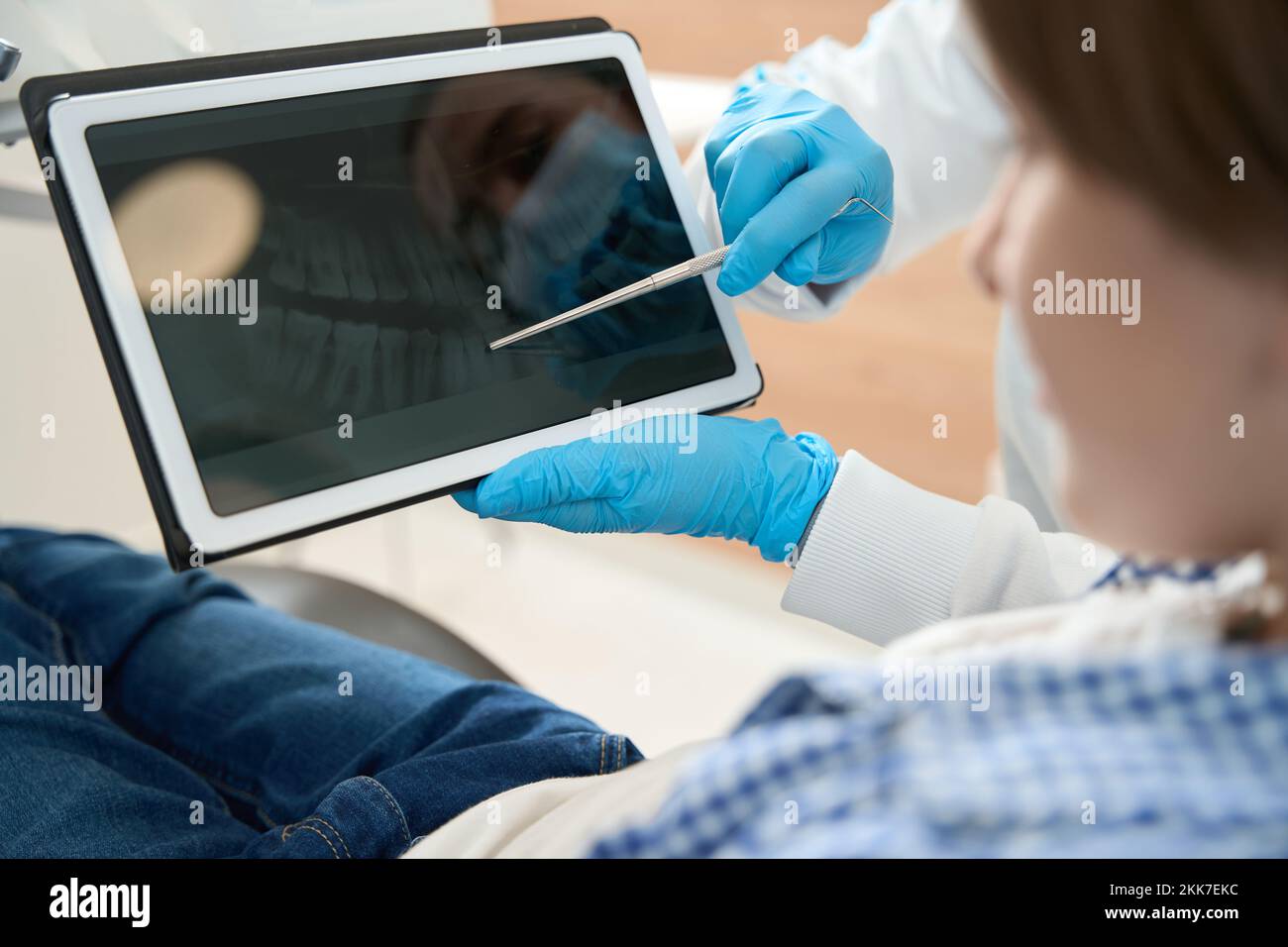 Dentist showing dental image on clipboard to young patient Stock Photo