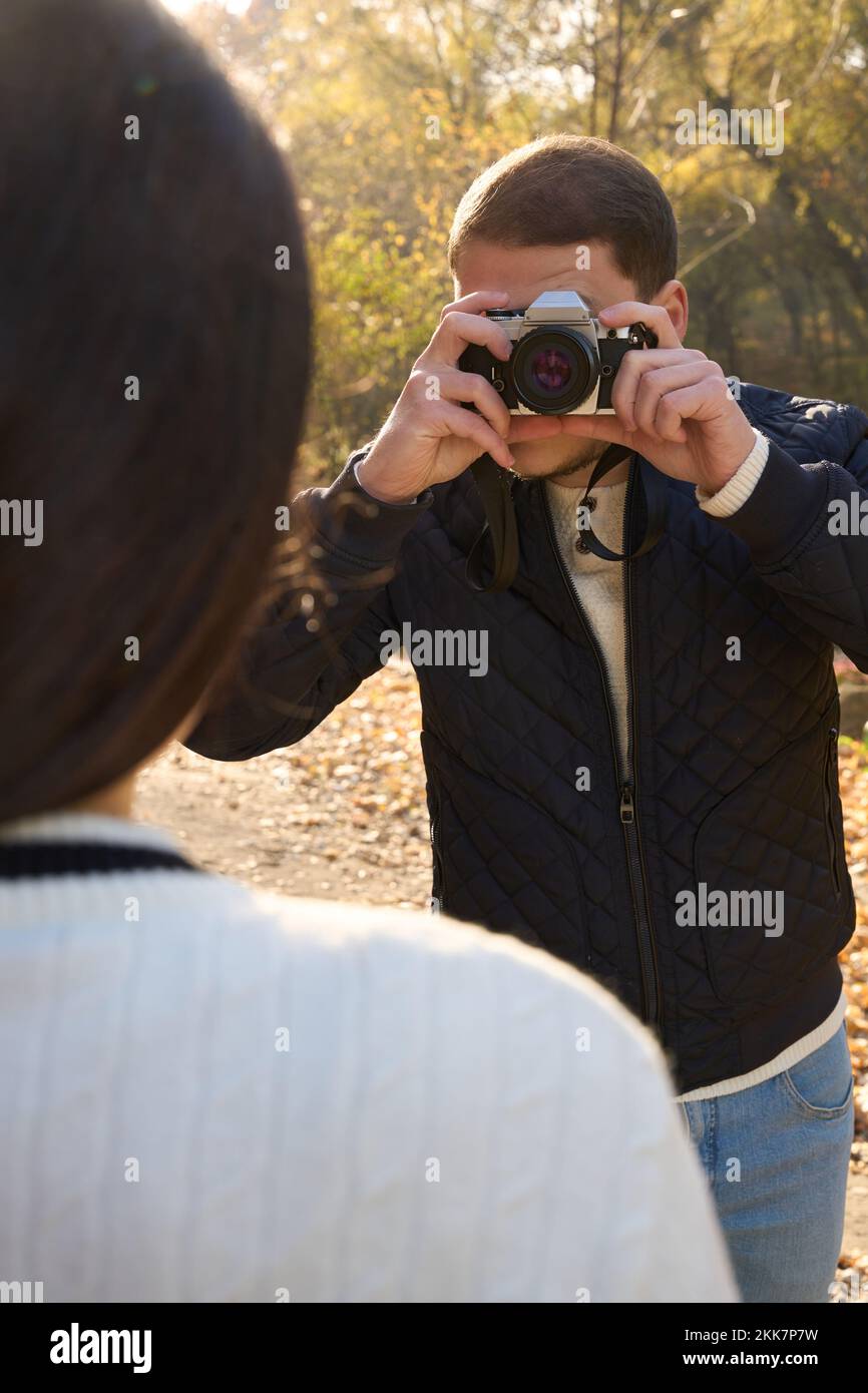 Guy in casual clothes holds a camera to his face Stock Photo