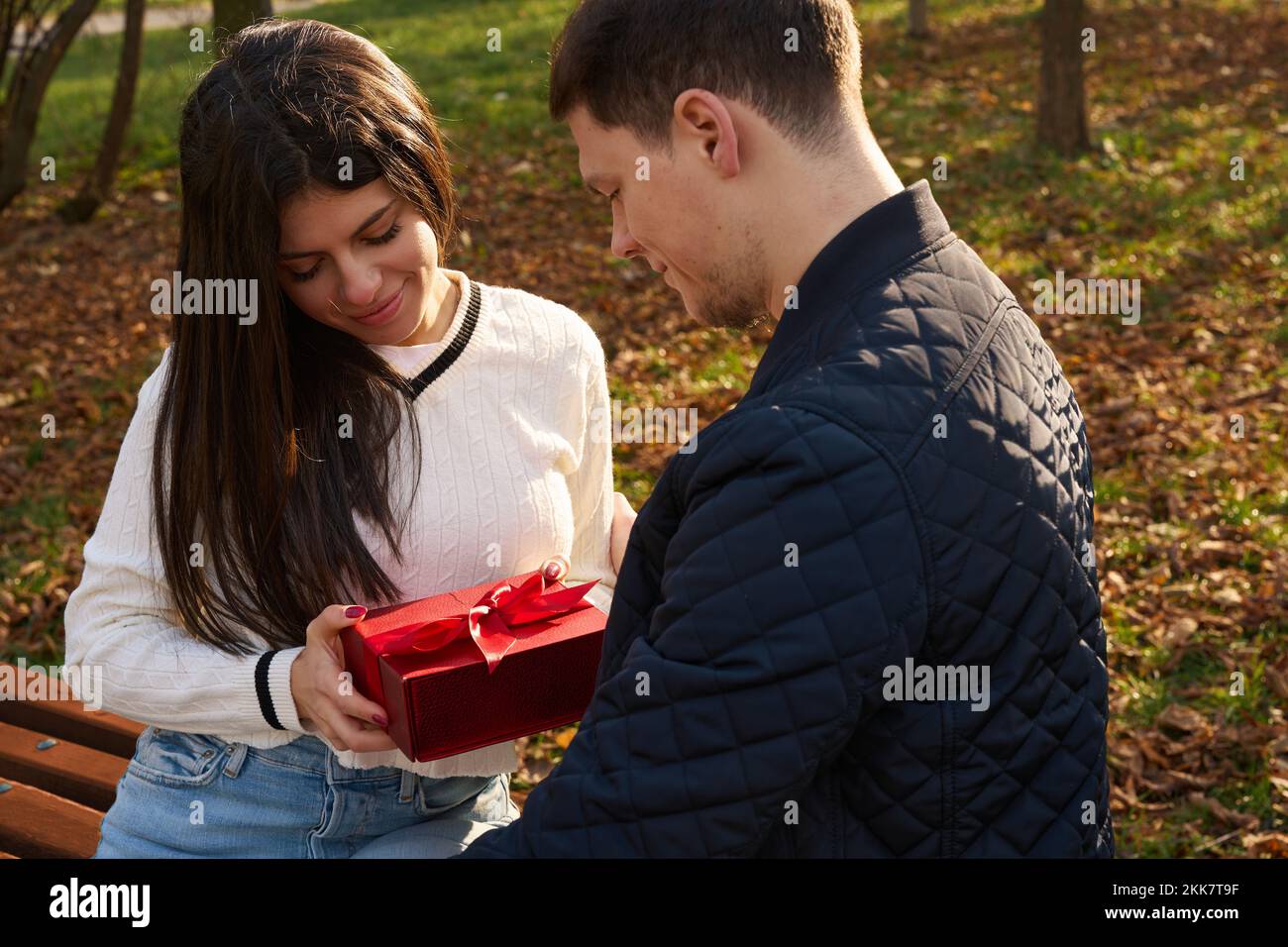 Pretty young woman accepts a gift box from her boyfriend Stock Photo