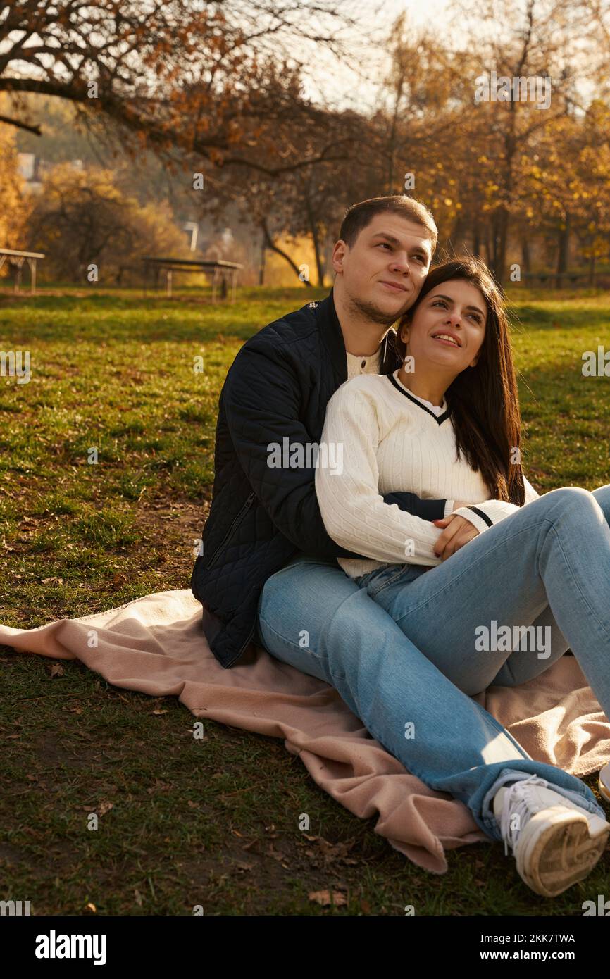 Couple is sitting on a lawn in a city park Stock Photo - Alamy