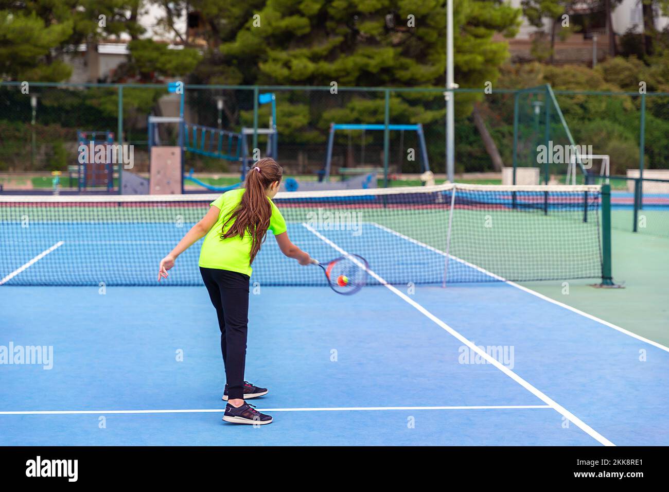 Young girl playing tennis. Serving the ball on tennis court. Stock Photo