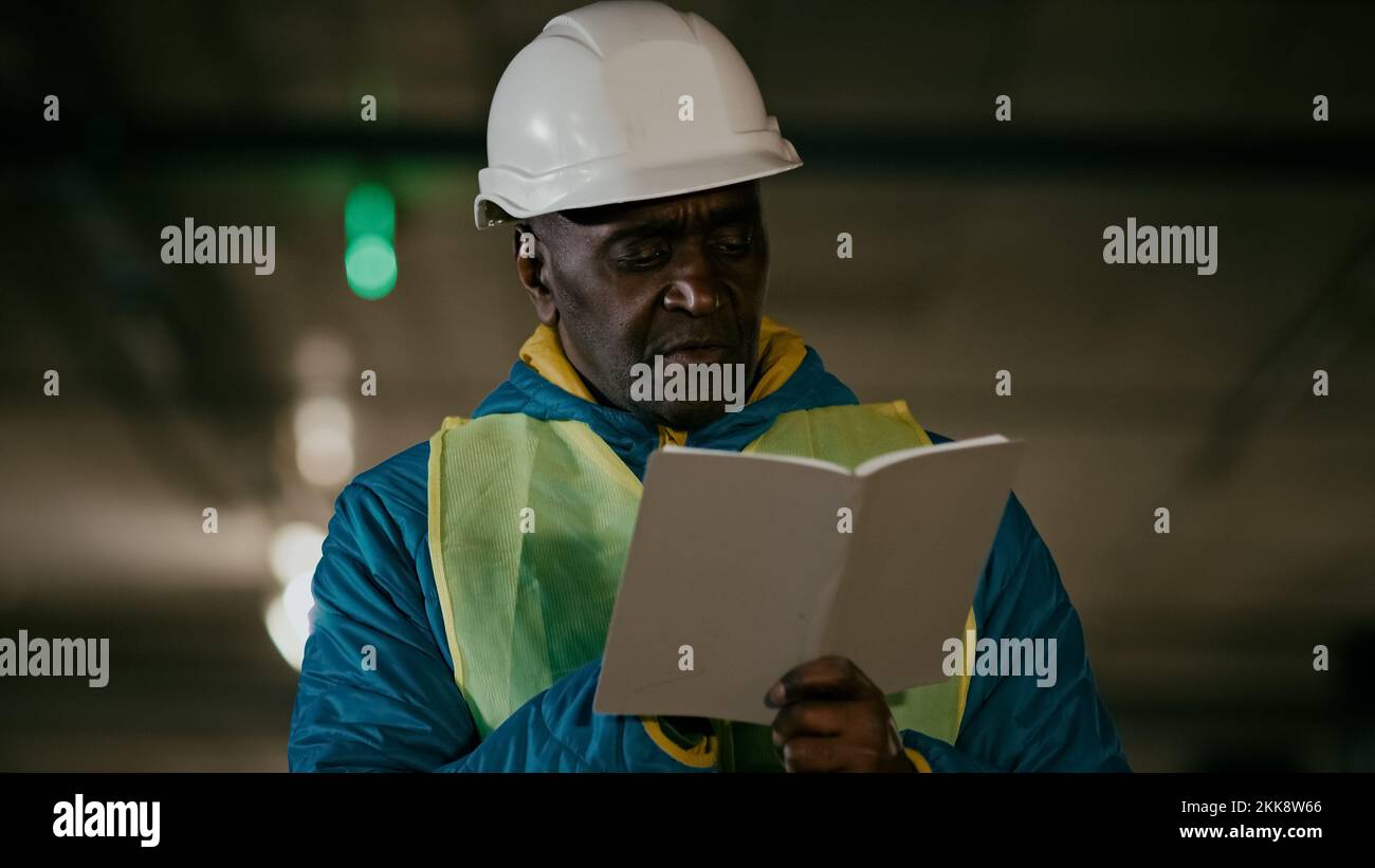 Mature man professional worker engineer builder with protective helmet inspects room writes data in notebook concentrated experienced foreman creates Stock Photo