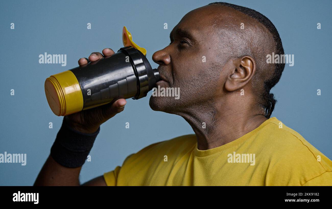 Close-up tired athletic man athlete taking break during training drinking cool fresh water from sports bottle quenches thirst after exercise adult Stock Photo