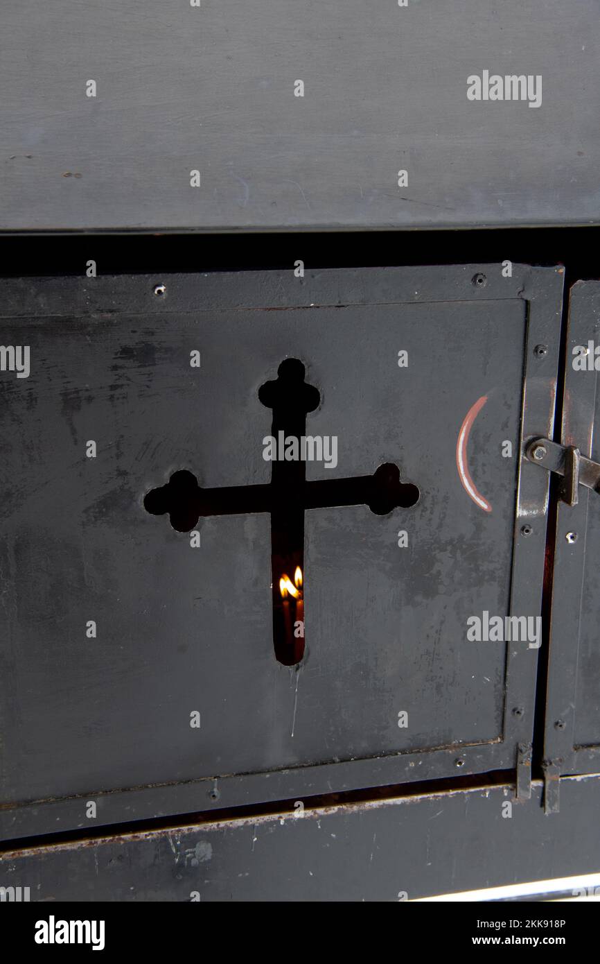 Sucevita, Romania, 2021-12-29. Metal chest with a crucifix-shaped hole in which candles are burning in the Sucevita monastery in the Bukovina region. Stock Photo