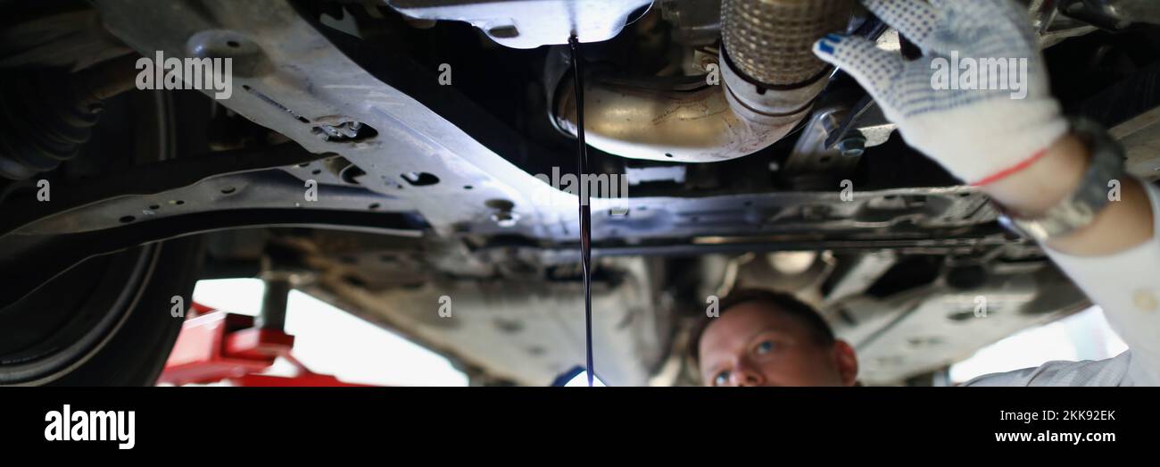 Mechanic man change oil under auto, car maintenance service, oil dripping Stock Photo