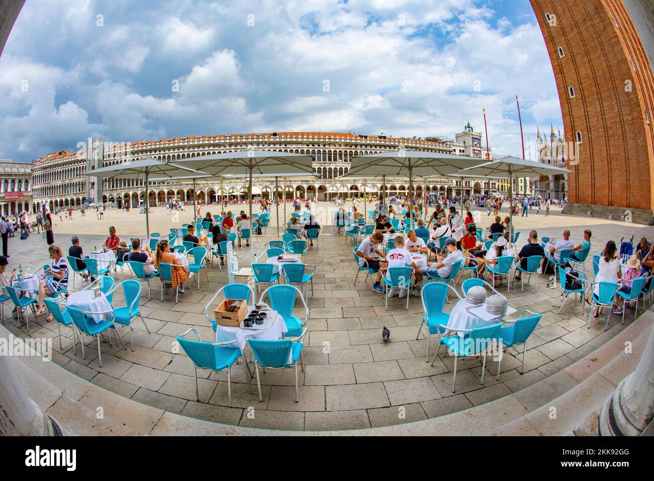 Venice, Italy - July 4, 2021:  view to San Marco square with campanile and basilica with tourists enjoying the view in an outdoor cafe at St. Mark's s Stock Photo