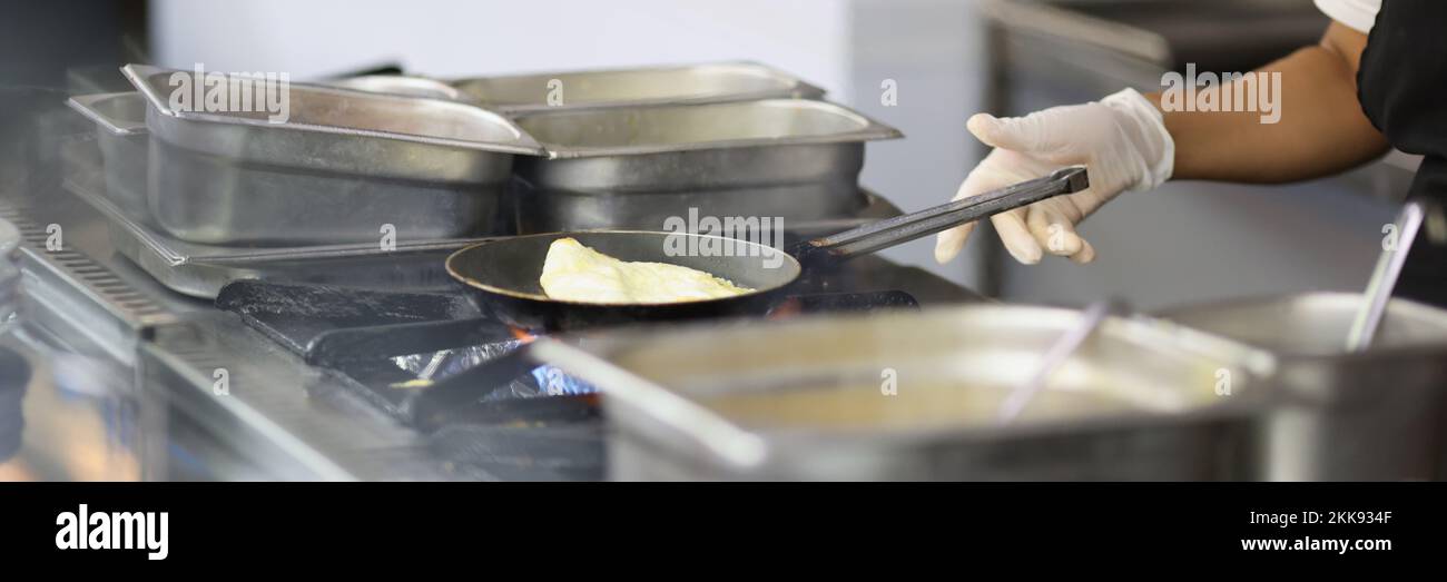 Cook prepares omelet in skillet in kitchen, cooking in cafes and restaurants Stock Photo