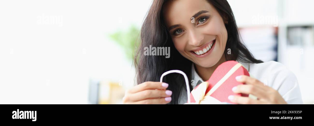 Brunette female happy to open festive box with present, curious and cheerful look Stock Photo