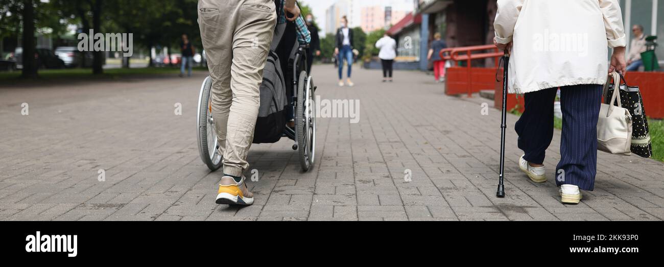 Man driving disabled woman in wheelchair across street, walking, shopping Stock Photo