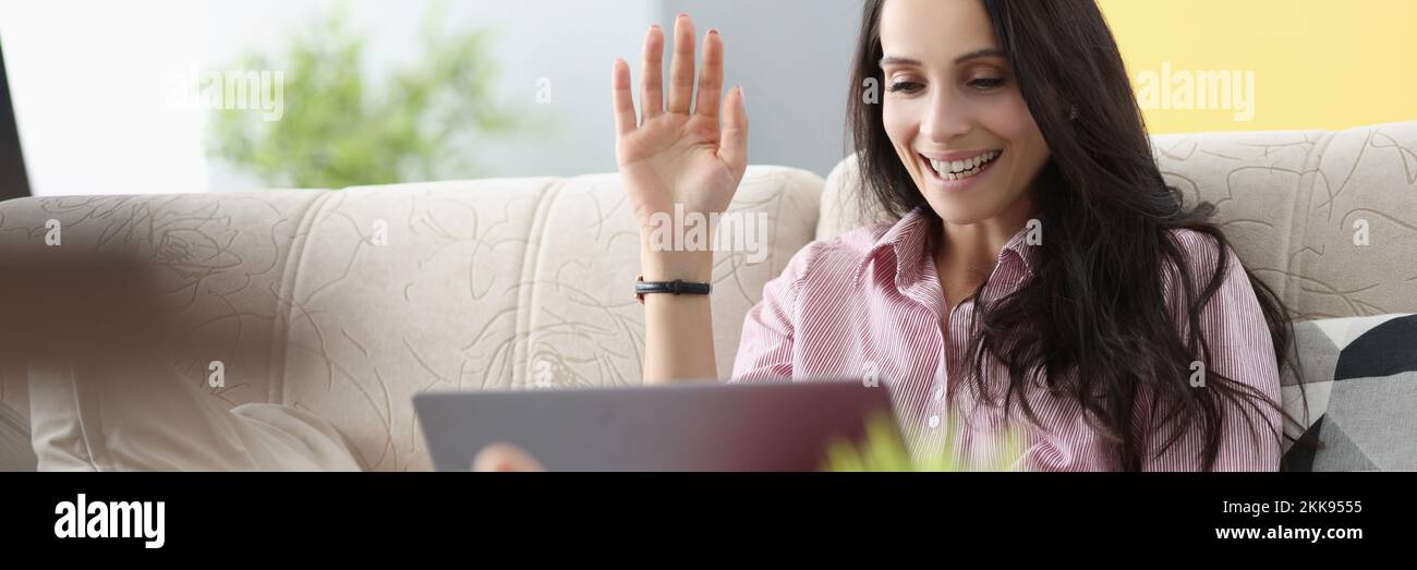 Woman wave hello, talk to friend via video call, happy to hear you Stock Photo