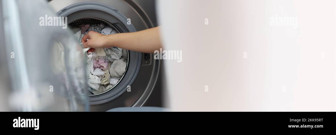 Woman loading washing machine with dirty clothes, taking out clean stuff Stock Photo