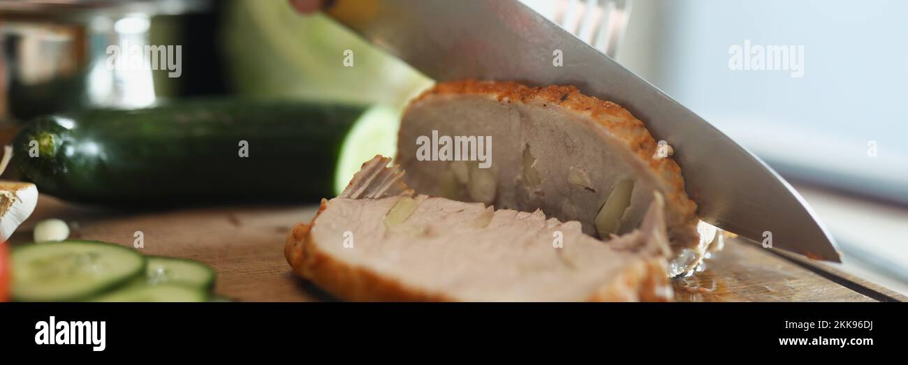 Person cutting homemade ham, delicious aromatic meat with garlic pieces Stock Photo