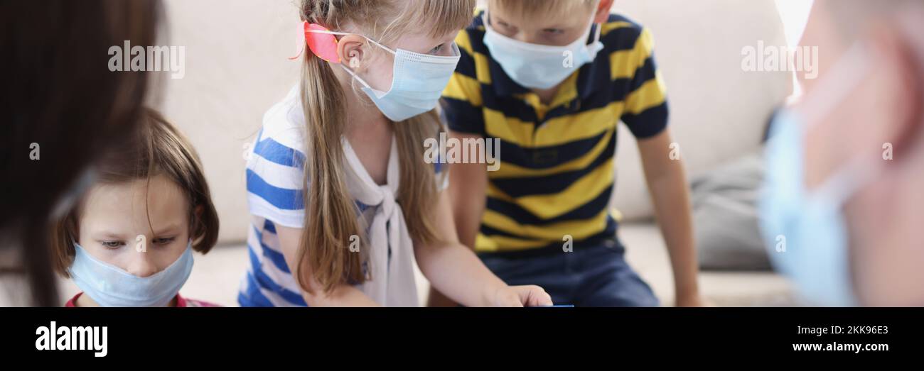 Kids in face masks, prevent virus spread in kindergarten, developing card game Stock Photo