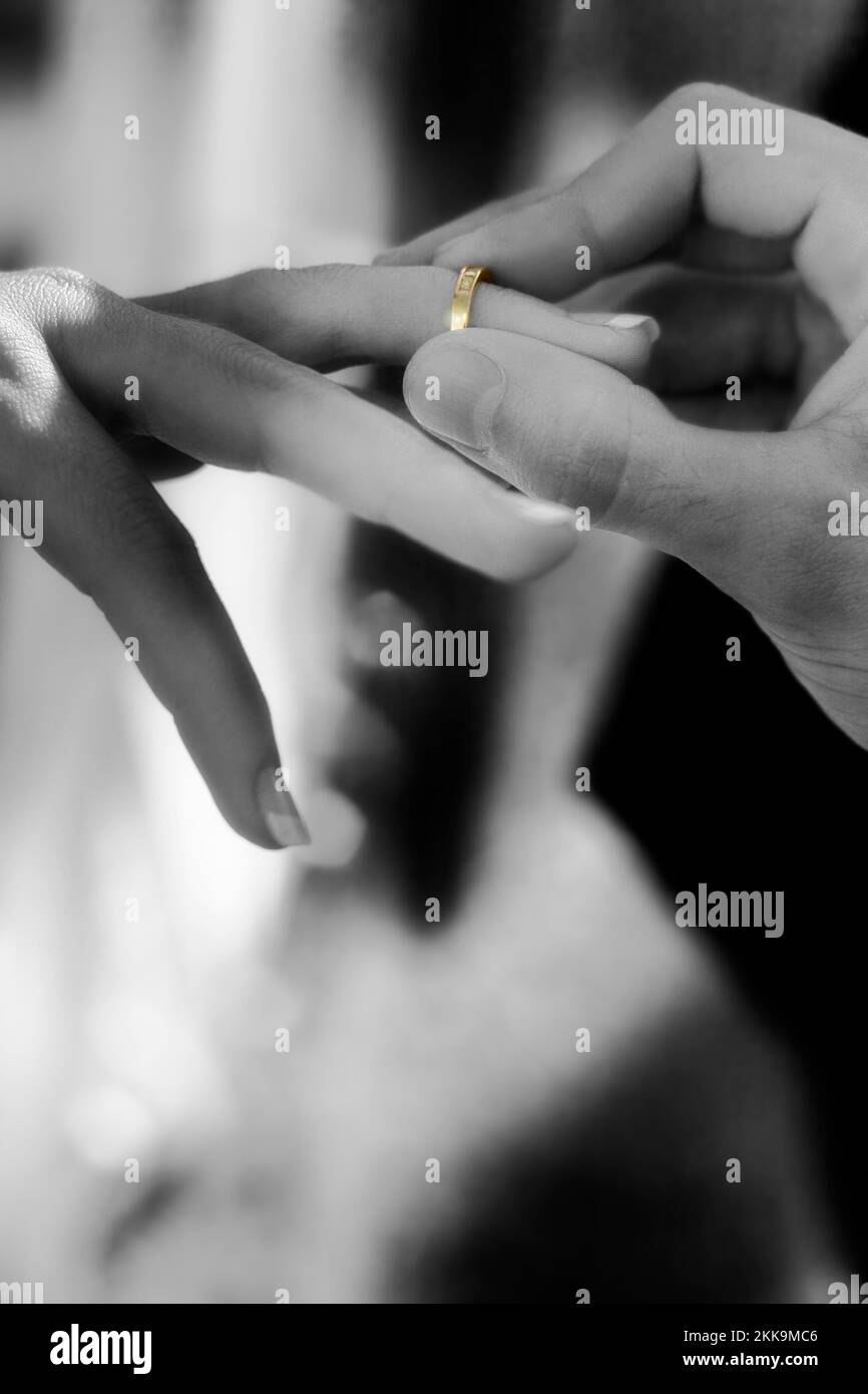 Black And White Photo Of A Groom Slipping A Gold Wedding Band On A
