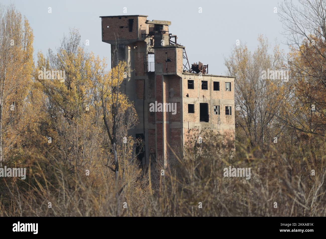 Abandoned oil mill surrounded by vegetation Stock Photo
