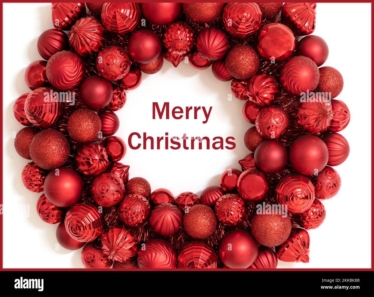 Merry Christmas holiday greeting card or background with green Happy Holidays text.  Red Wreath made of red christmas ornaments. Stock Photo