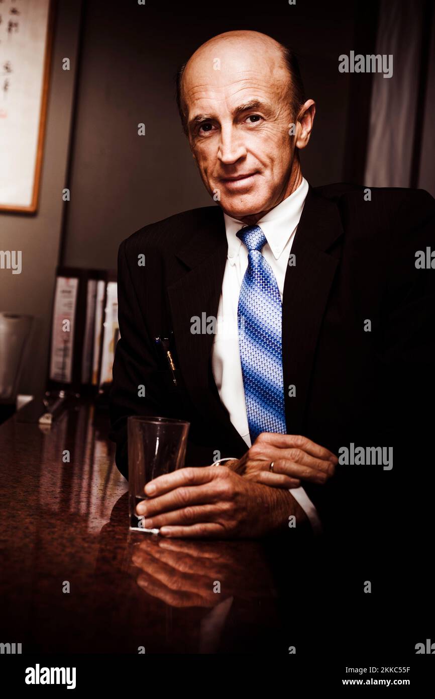 Travelling Elderly Executive Businessman Looking Pensive When Standing At A Hotel Table With