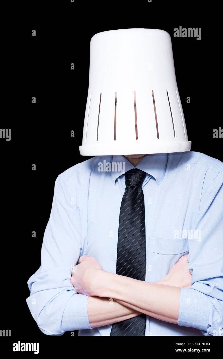 Business Person Under Stress Hiding Under Waste Paper Bin On Black Background Stock Photo