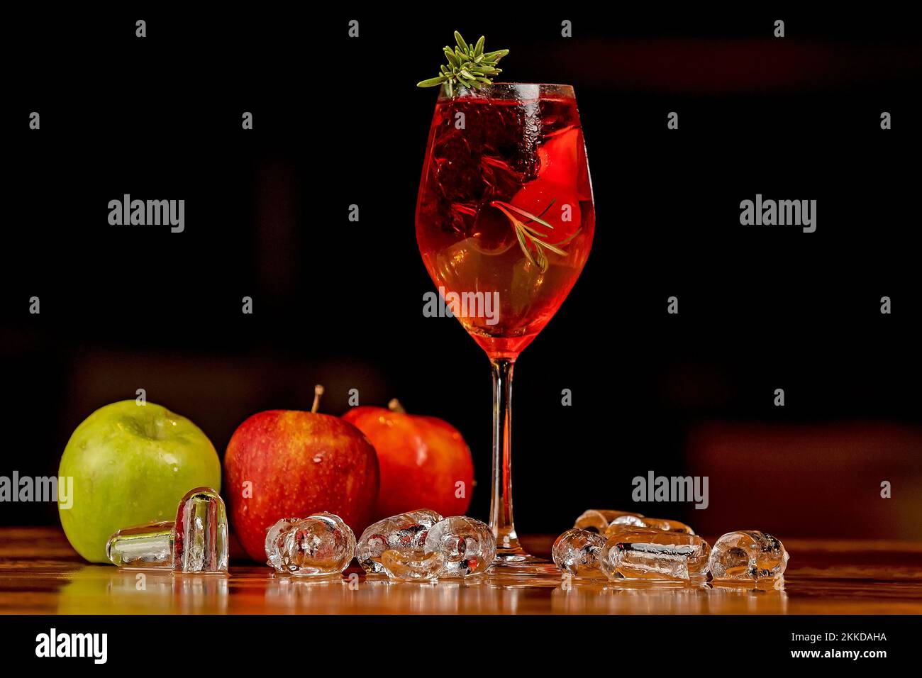 A glass of cold delicious apple juice, ice cubes, and green and red apple on a table Stock Photo