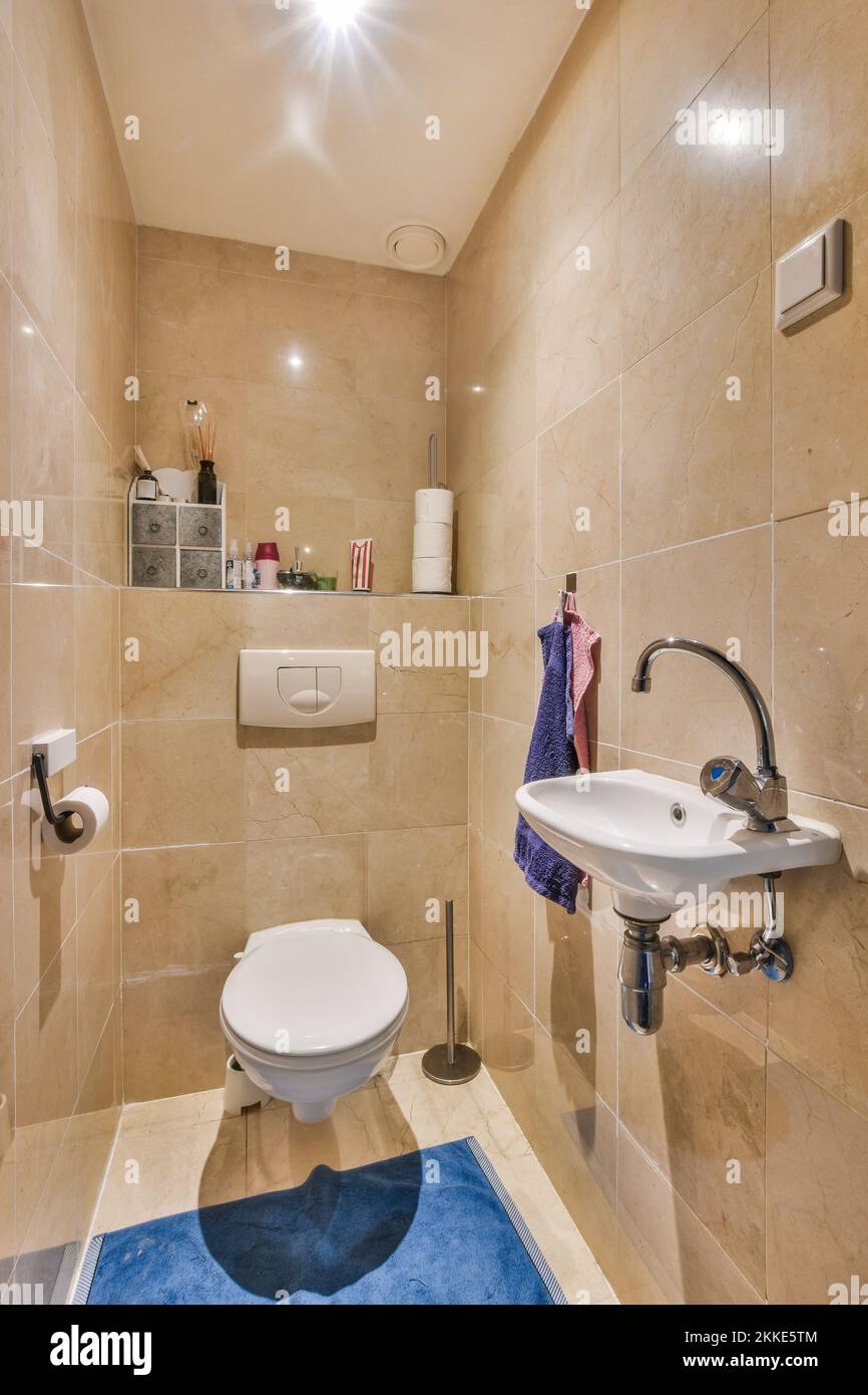 Modern toilet installed on beige wall under button and illuminated