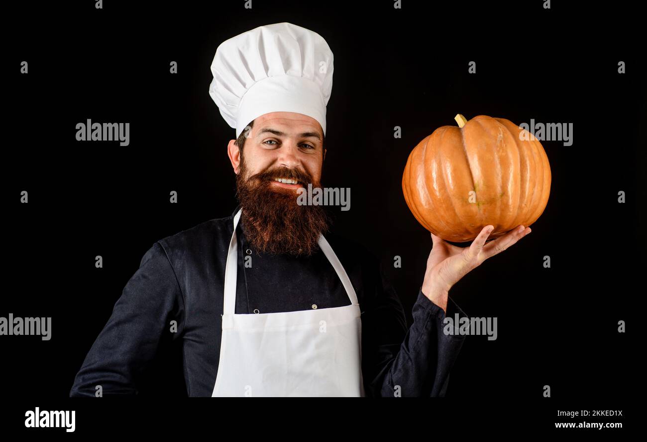 Bearded cook in chef uniform and apron with pumpkin. Healthy organic harvest vegetable. Autumn food Stock Photo