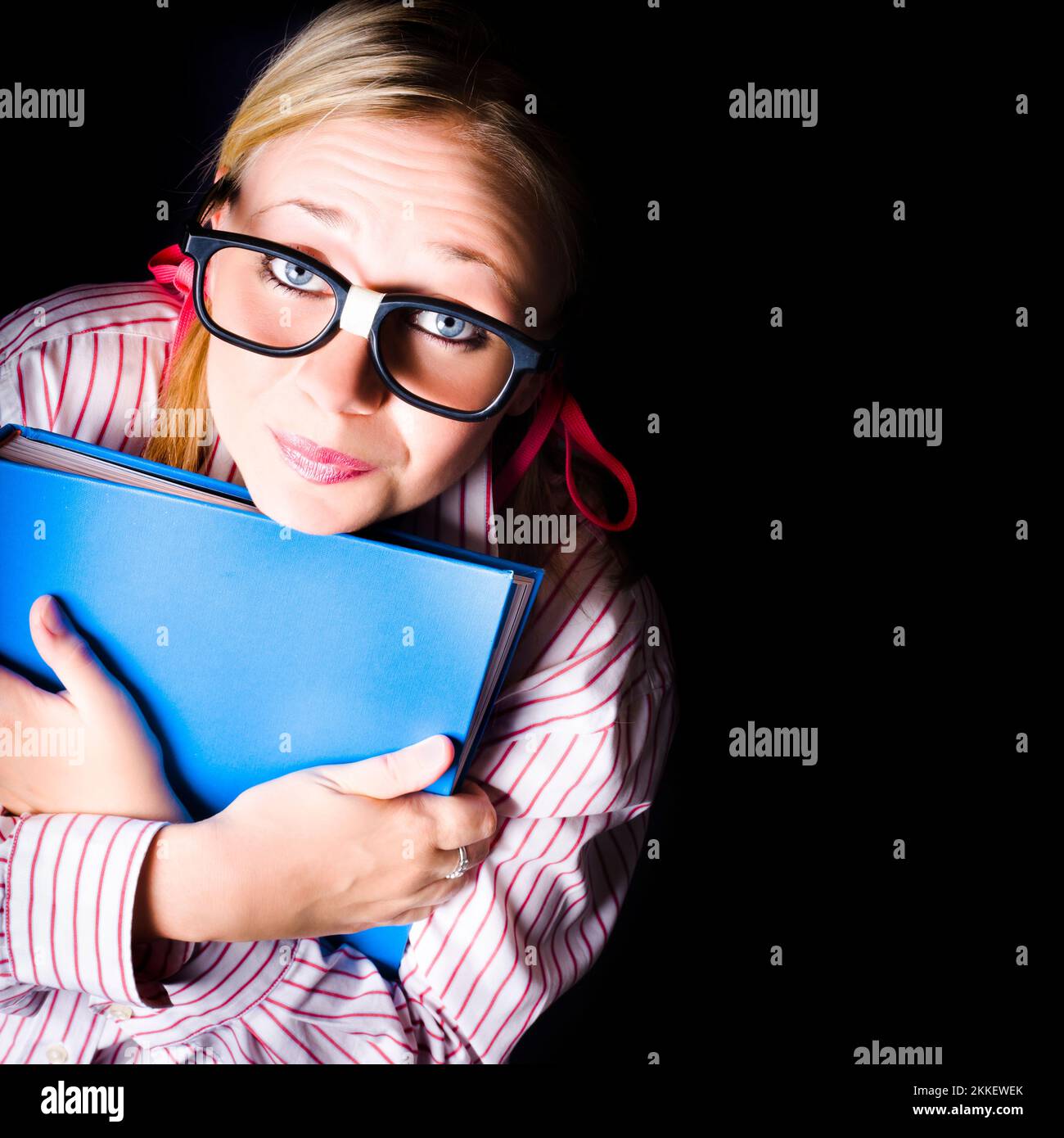 Cute geeky school student holding educational book on black copyspace