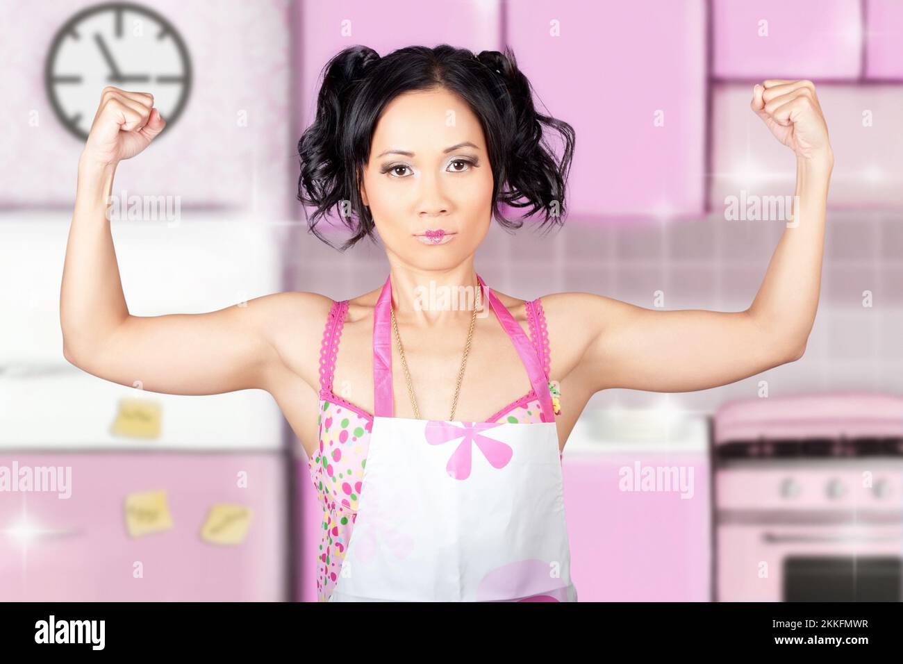 Funny cleaning pinup woman wearing apron flexing muscles in home kitchen when showing the power of clean Stock Photo