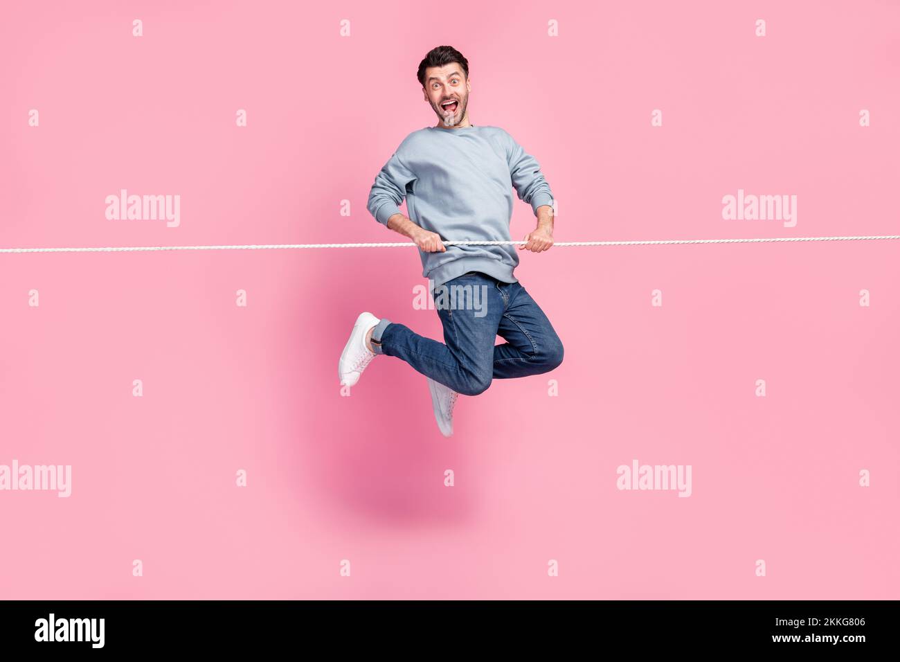 Full length photo of playful guy jumping up supporting by string ...