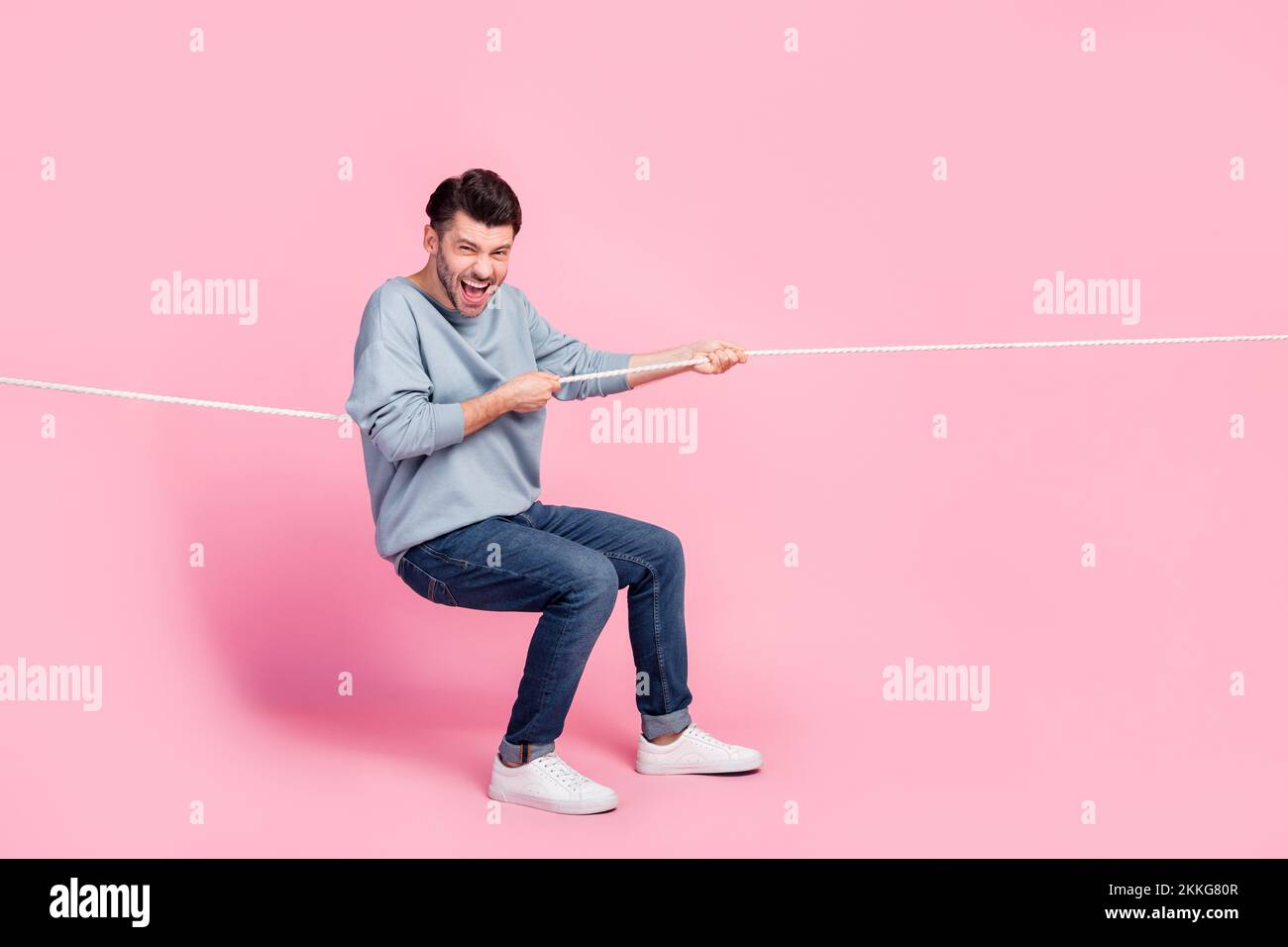 Full length photo of excited guy competitor pulling tug war string ...