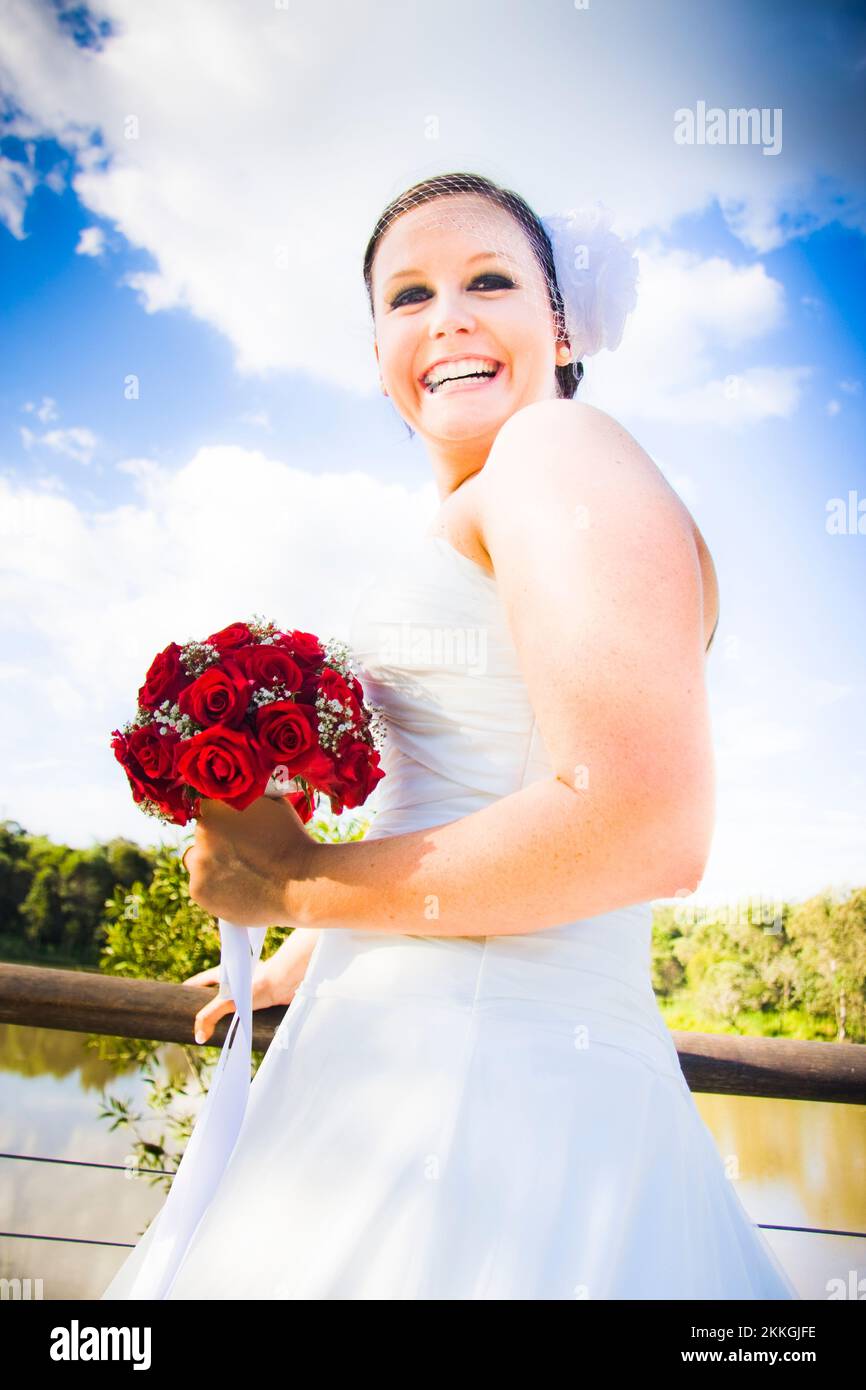 A Young Beautiful Bride Wearing A White Dress And Carrying Red Rose